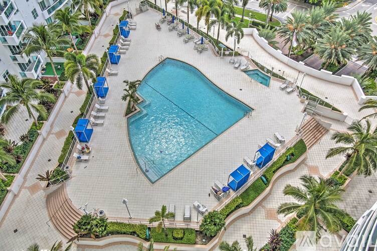 An aerial view of a pool surrounded by palm trees and lounge chairs.