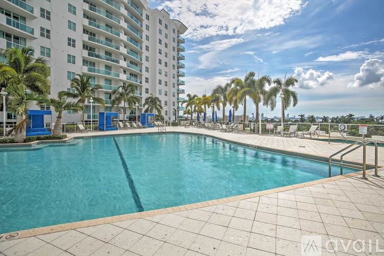 A large swimming pool in front of a white building with palm trees.