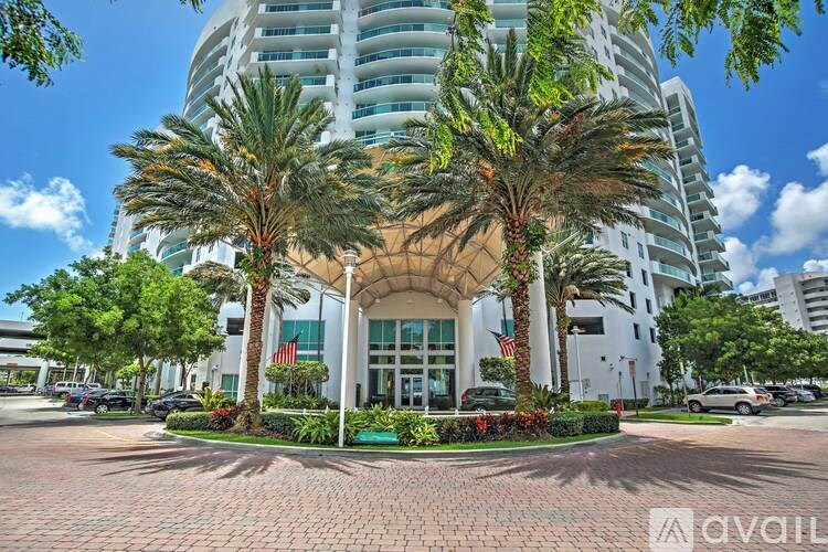 A tall building with a glass facade and palm trees in front.