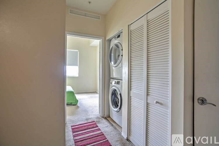 A laundry room with a washing machine and a red rug.