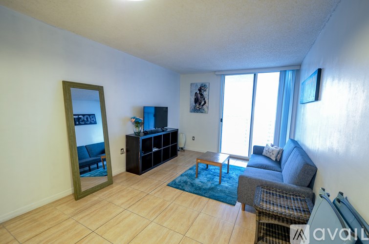 A living room with a grey couch, a blue rug, and a wooden floor.