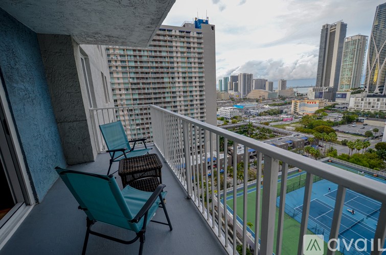 A balcony with a chair and table overlooking a cityscape.