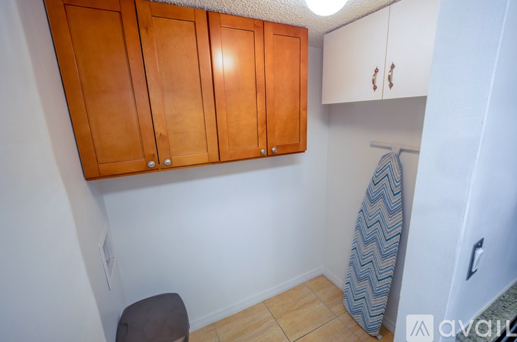 A small room with wooden cabinets and a towel hanging on a hook.