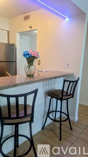 Two chairs are placed in front of a counter with a vase of flowers on it.