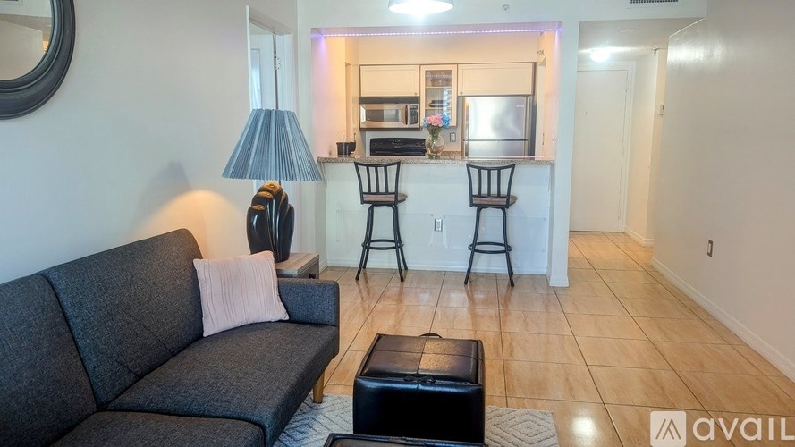 A living room with a grey sofa and a black ottoman.