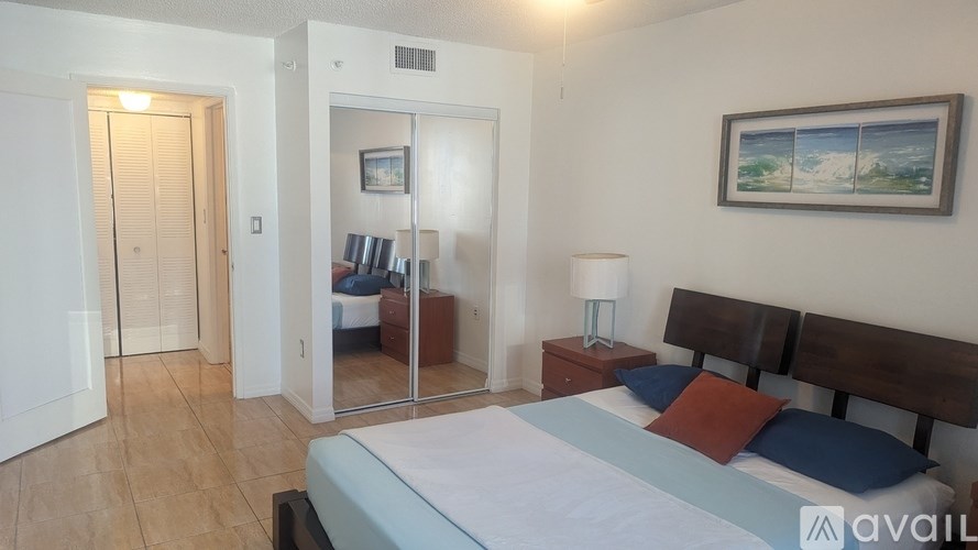 A bedroom with a bed, nightstand, and a painting on the wall.