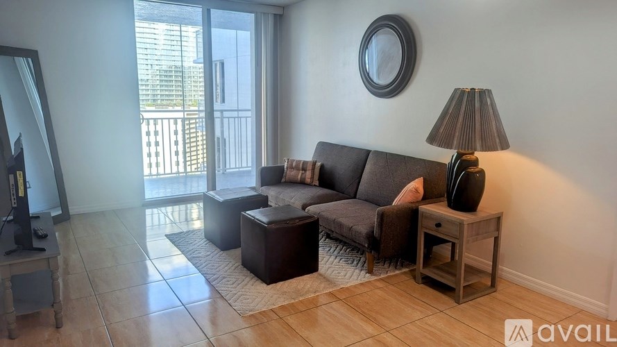 A living room with a grey couch, a brown side table, and a large window.