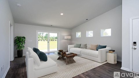 A living room with white furniture and a large window.