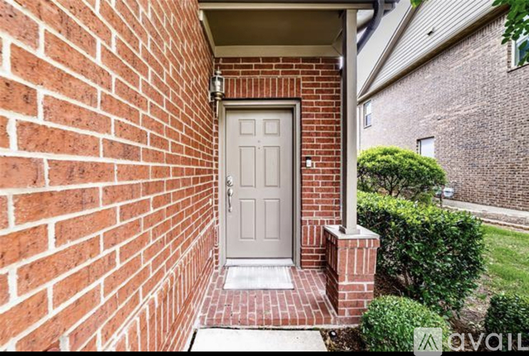 A white door is on the left side of a brick wall.