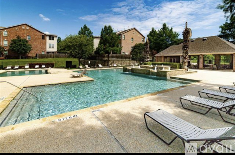 A pool with sun loungers and a building in the background.