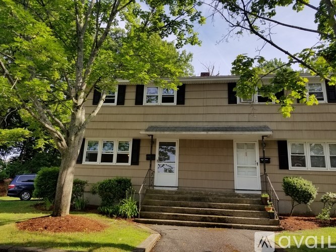 A house with a white door and a tree in front.