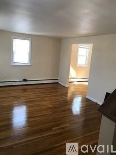 A room with wooden floors and two windows.