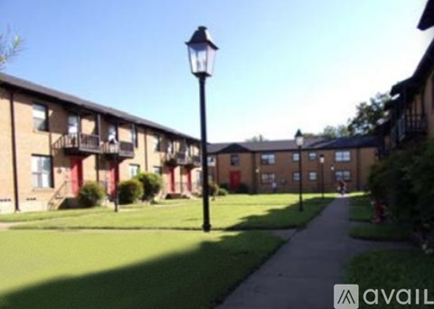 A black lamp post stands on a grassy area in front of apartment buildings.