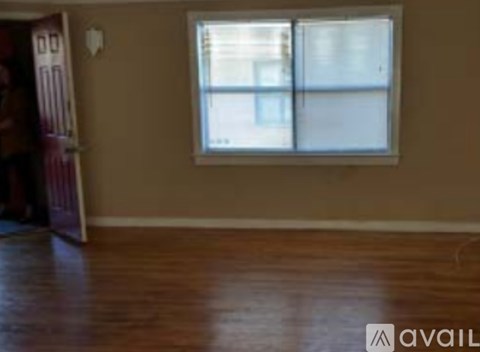 A room with a window and wooden flooring.