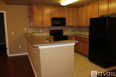A kitchen with wooden cabinets and a black refrigerator.