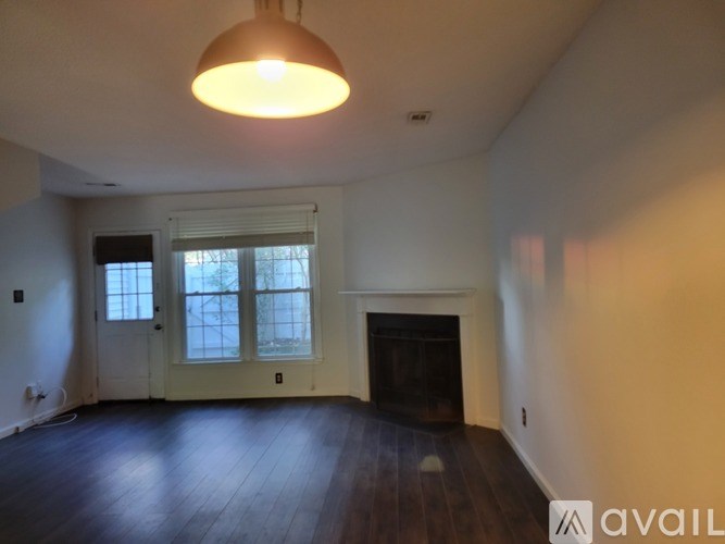 A large empty room with a fireplace and a window.