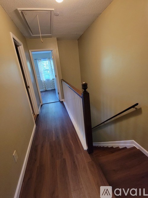 A hallway with wooden floors and a white door.
