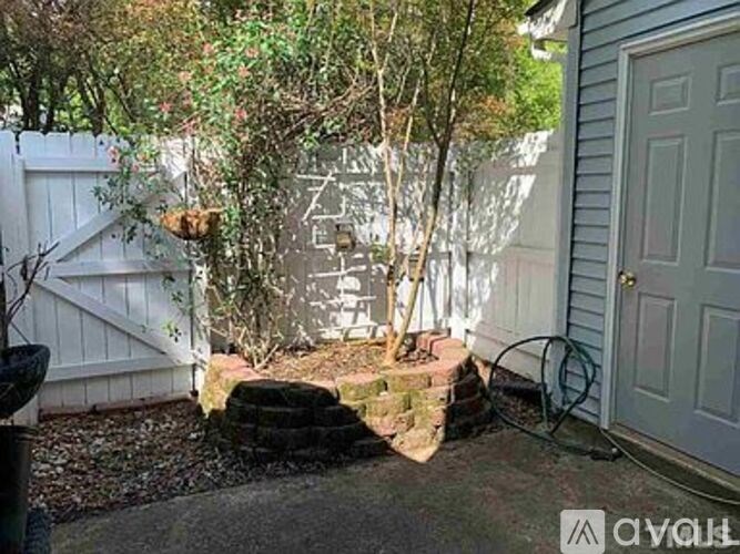 A backyard with a white fence and a tree.