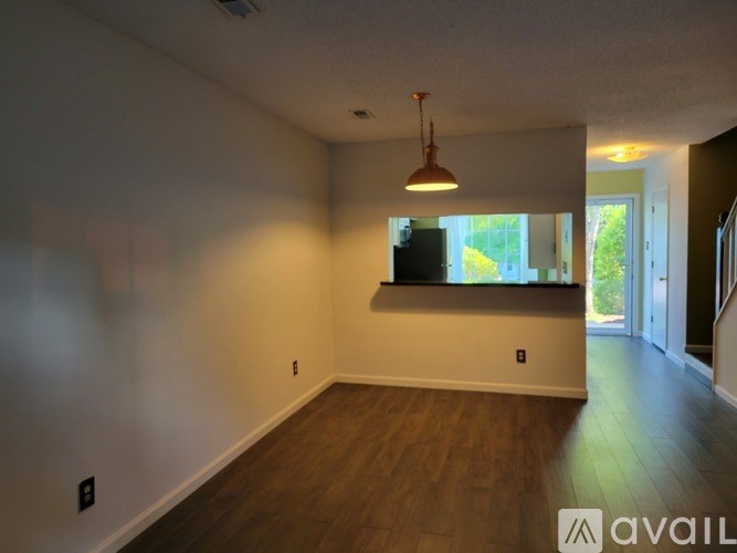 A room with wooden floors and a window with a view of trees outside.