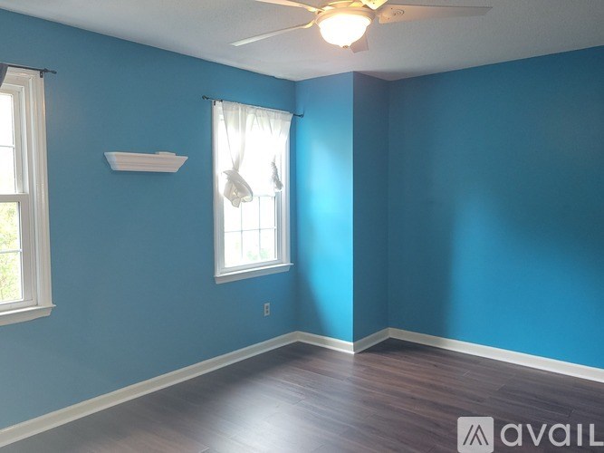 A room with blue walls and a window with white curtains.