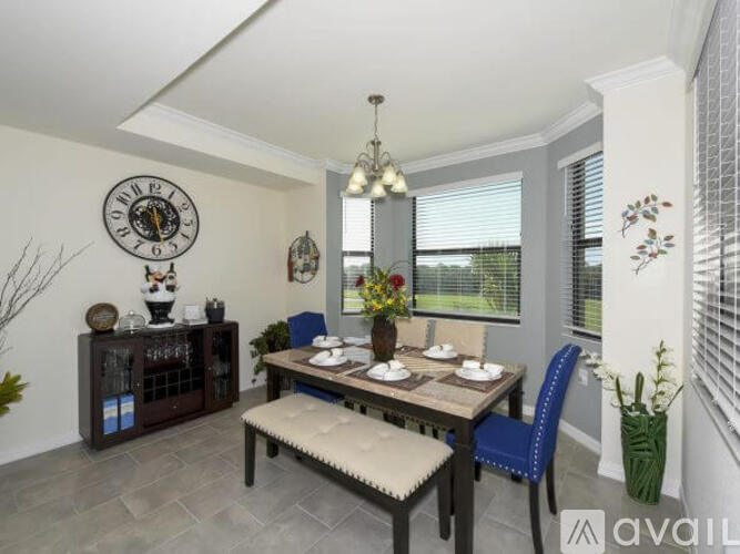 A dining room with a table set for two and a clock on the wall.