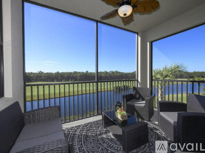 A patio with a table and chairs overlooking a pool and a field.