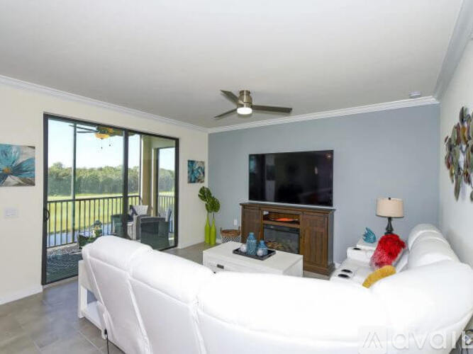 A living room with a white couch and a flat screen TV.
