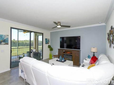A living room with a white couch and a flat screen TV.