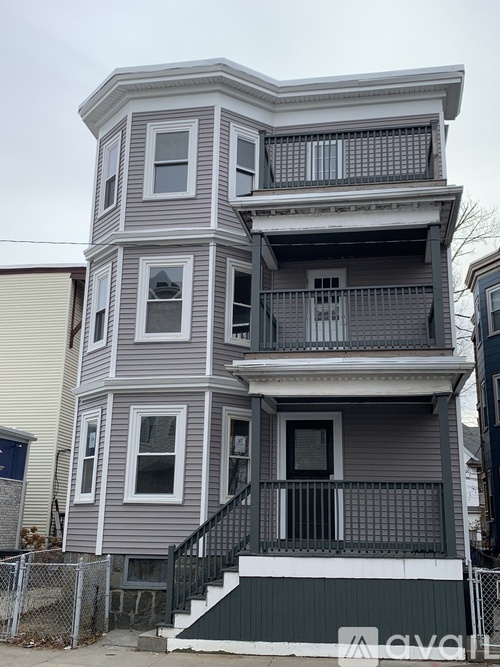 A grey two-story house with a balcony and a staircase leading to the second floor.