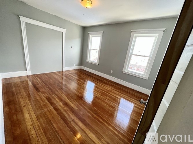 A room with wooden floors and two windows.