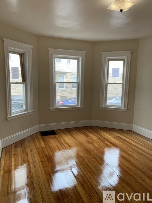 A room with wooden floors and three windows.