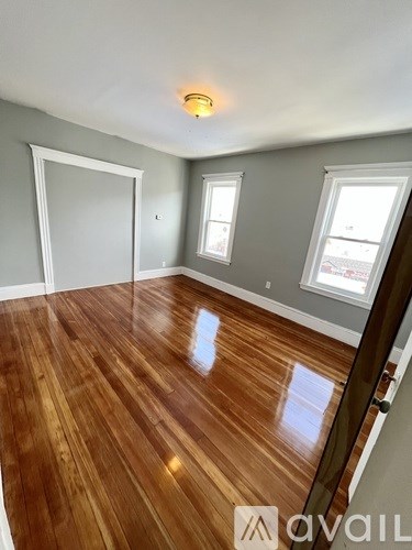 A room with wooden flooring and a window on the right side.