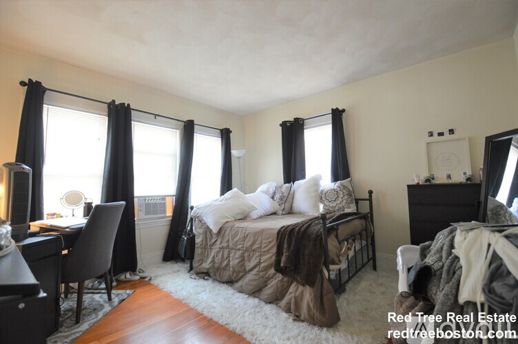 A bedroom with a bed, desk, and chair.