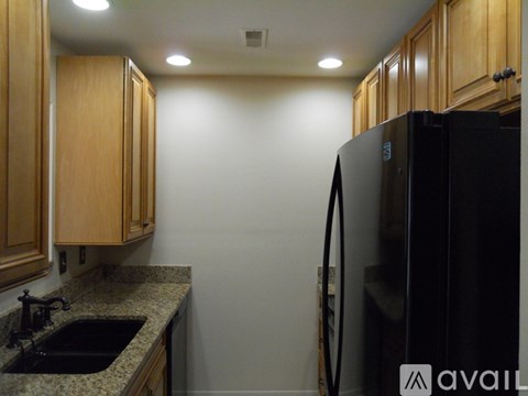 A kitchen with wooden cabinets and a black refrigerator.