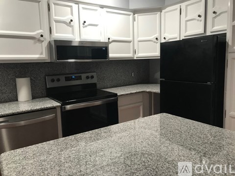 A kitchen with white cabinets and a black refrigerator.