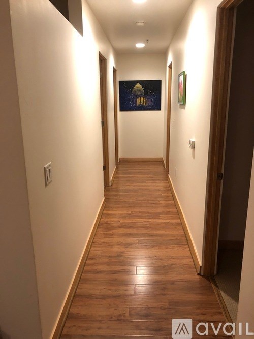 A long hallway with wood floors and a painting on the wall.