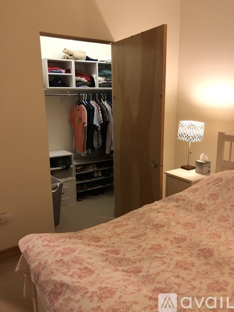 A bedroom with a bed, a wardrobe, and a nightstand with a lamp.