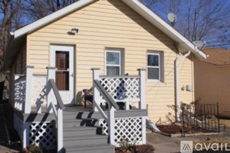 A yellow house with a white porch and a dog on the steps.