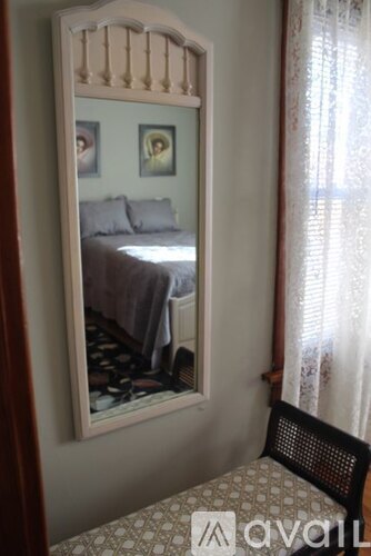 A bedroom with a bed and a mirror on the wall.
