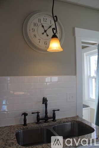 A kitchen with a clock on the wall and a sink below it.