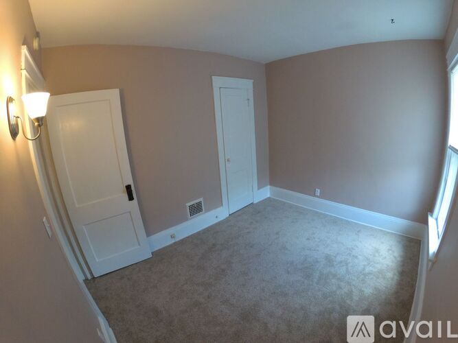 A room with a carpeted floor and two doors.