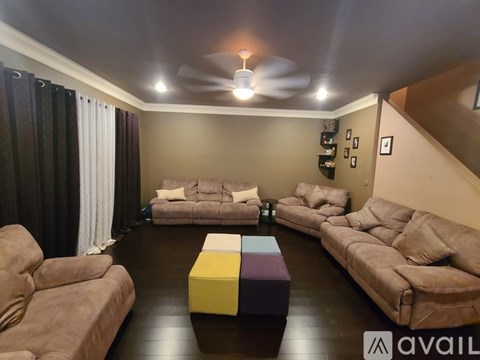 A living room with brown couches and a yellow and purple ottoman.