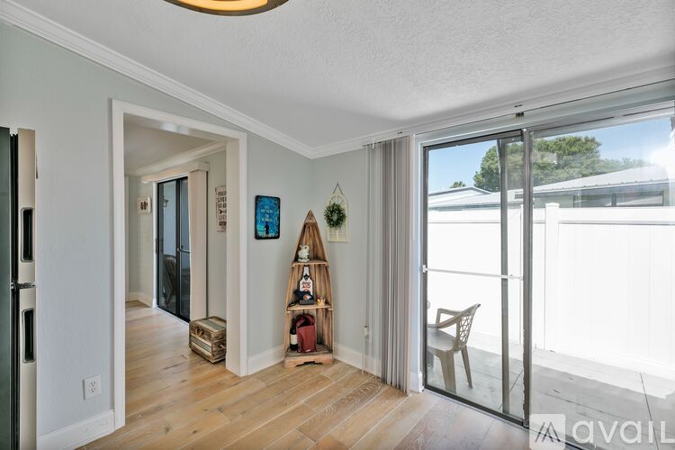 A room with a wooden floor and a white wall with a hanging decoration.
