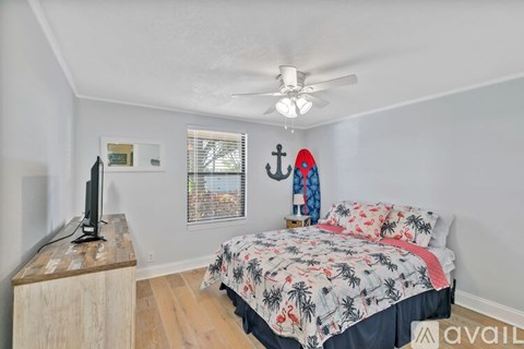 A bedroom with a bed, a television, and a window with blinds.