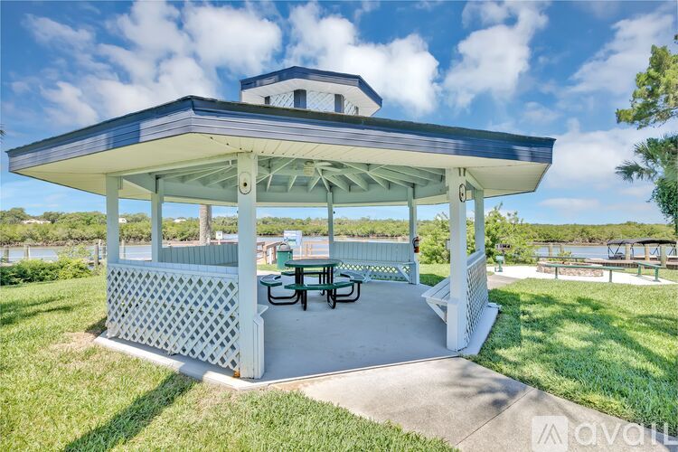 A pavilion with a table and chairs is set up in a grassy area.