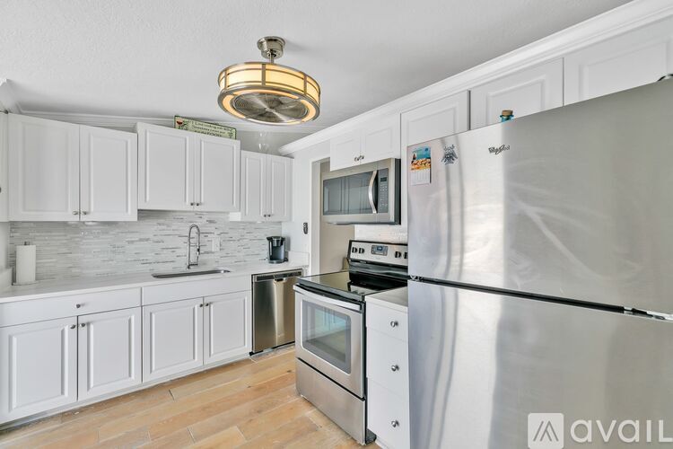 A kitchen with white cabinets and a stainless steel refrigerator.
