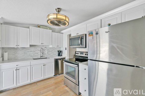 A kitchen with white cabinets and a stainless steel refrigerator.