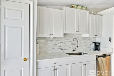 A kitchen with white cabinets and a white door.