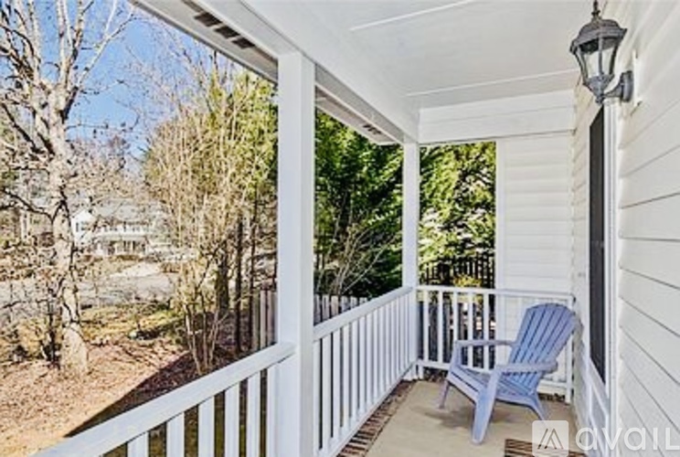 A blue chair sits on a porch with a view of trees.