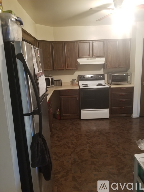 A kitchen with a black refrigerator and brown cabinets.